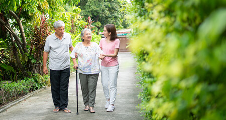 Happy family walking together in the garden. Old elderly using a walking stick to help walk balance. Concept of  Love and care of the family And health insurance for family