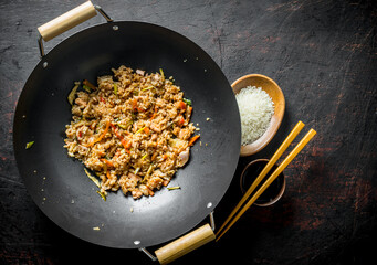 Chinese wok. Cooked rice in a wok pan and uncooked rice on a plate.