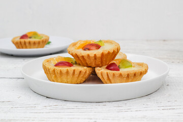 Small fruit pia cake on a textured white background. Kue Pia Buah.