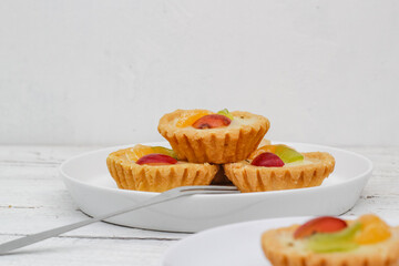 Small fruit pia cake on a textured white background. Kue Pia Buah.