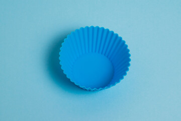 Blue silicone mold for a cupcake on a light blue paper background