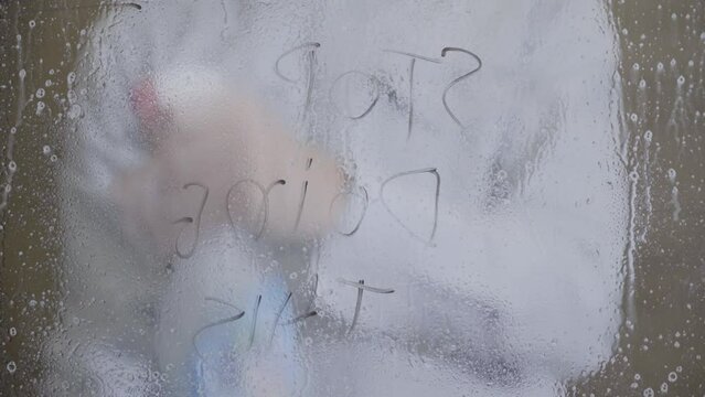young man cleans windows with spray at home