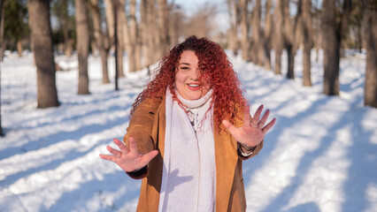 Cheerful fat caucasian woman walks in the park in winter.