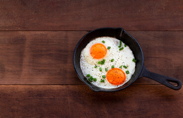Healthy breakfast food fried egg in skillet pan on wood table.