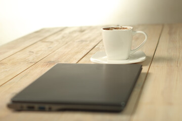 a cup with coffee behind a laptop