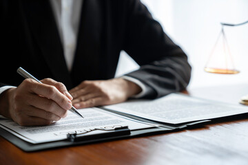 Young Asian legal advisor or lawyer reading financial details investment agreement Signing a contract for validity before the delivery of documents to help his clients succeed.