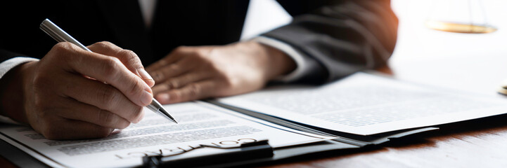 Young Asian legal advisor or lawyer reading financial details investment agreement Signing a contract for validity before the delivery of documents to help his clients succeed.