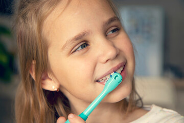 Close-up of a little girl brushing her teeth with an electric toothbrush. The concept of modern oral care, morning or evening care for teeth and gums. Child's personal hygiene