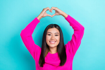 Obraz na płótnie Canvas Photo of cheerful japanese young attractive woman wear pink knitted sweater raise hands show love symbol date isolated on cyan color background