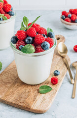 Delicious italian dessert panna cotta with fresh raspberry, blueberries and mint on gray marble background