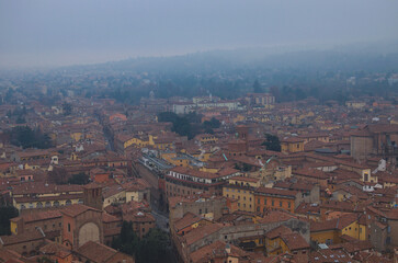 Fototapeta premium Scenic bird-eye view from the top of the tower on Bologna old town center. Vintage buildings with red tile roofs. Famous touristic place and travel destination in Europe. UNESCO World Heritage Site