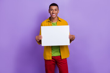 Portrait of good mood cheerful optimistic nice man wear yellow clothes hands holding white banner isolated on pastel color background