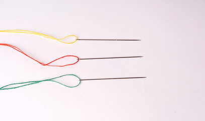 Colorful sewing thread set and needles isolated on background.