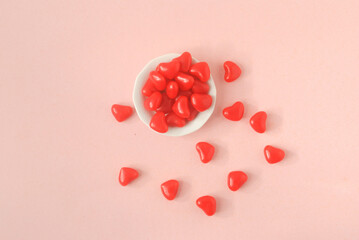 heart shaped candy on a white plate in a pink background 