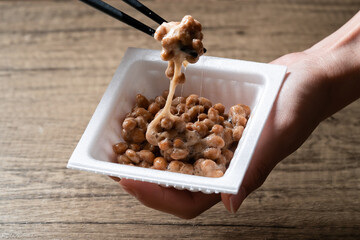Natto being lifted by chopstick in isolated wooden background