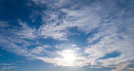 Naklejka na ściany i meble Sunbeams among white clouds in blue sky. sky background