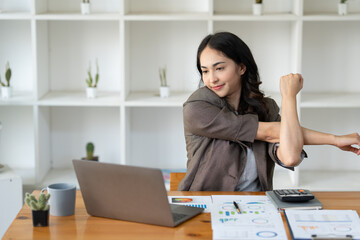 A young Asian businesswoman sits in a chair relieved from fatigue as she sits in the office with a...
