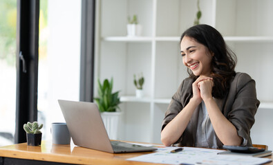 Young Asian businesswoman sitting with her hands on the desk with a happy smile at successful work The results were as planned. management concept management.