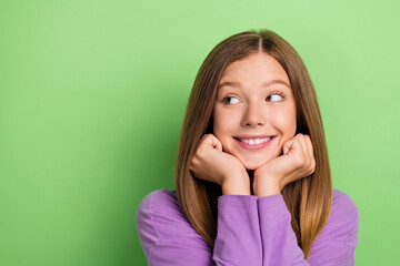 Portrait of cute cheerful girl long hairstyle purple long sleeve arms on cheekbones look empty space isolated on green color background