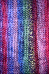 Fototapeta premium texture of red burgundy multicolored knitted sweater close-up, purple wool knitted front surface, gray telpai background, concept, hand knitted banner, hand knitting texture, front surface
