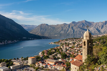 Naklejka na ściany i meble Panoramic view from Kotor city walls on Church of Our Lady of Remedy and Kotor bay in sunny summer, Adriatic Mediterranean Sea, Montenegro, Balkan Peninsula, Europe. Fjord winding along coastal towns