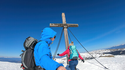 Couple reaching the summit cross of mountain peak Ladinger Spitz, Saualpe, Lavanttal Alps, border...