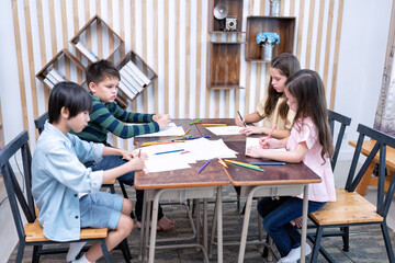 Children in class room happy laughing enjoy draw picture on paper and show to friend