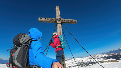 Couple reaching the summit cross of mountain peak Ladinger Spitz, Saualpe, Lavanttal Alps, border...