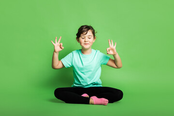 Girl sitting in lotus pose and showing ok gesture