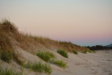 Atardecer sobre las dunas de la playa. El cielo se llena de colores y el ambiente se torna relajado, tranquilo.