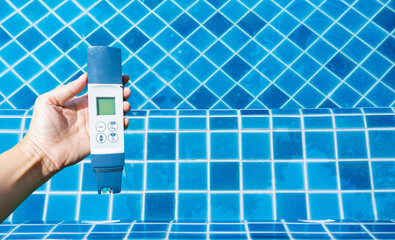 Digital water tester in girl hand over crystal clear water with blue tile floor, summer outdoor day light, quality water tester