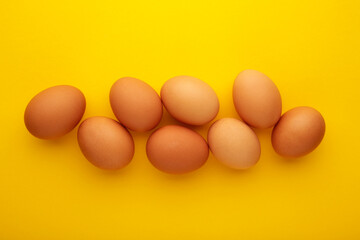 Chicken eggs on yellow background. Farm products, natural eggs.