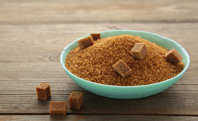 Brown sugar and sugar cubes on grey wooden background.