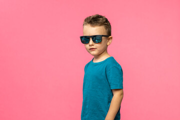 Stylish cute little boy posing on pink background.