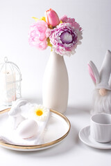 Easter festive table with white eggs and a bouquet of flowers in a vase. Bright Easter
