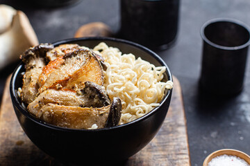 Noodles with eringi mushrooms in a black plate