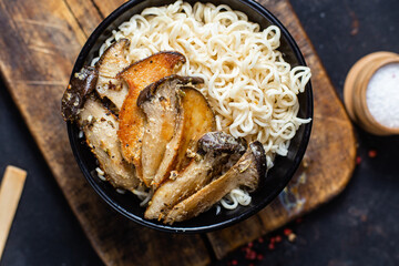 Noodles with eringi mushrooms in a black plate