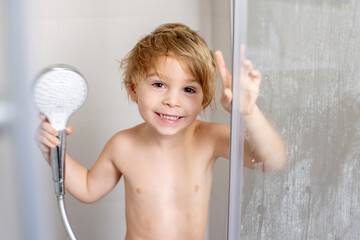 Sweet toddler boy in bathroom, taking shower, smiling happily - obrazy, fototapety, plakaty