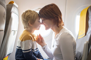 Mother and child, boy and mom, sitting in airplane, child playing on tablet