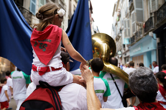 Petite fille sur les épaules de ses parents au défilé des bandas des Fêtes de Bayonne