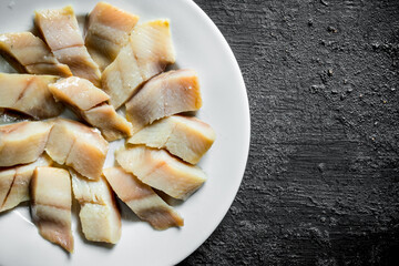 Pieces of salted herring on a plate.