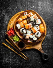 Fresh sushi rolls in a plate on a cutting Board with chopsticks and sauces.