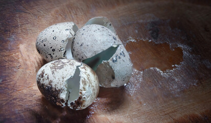 The shell of broken three quail eggs lies on a wooden surface next to a leaked squirrel. Selective,...