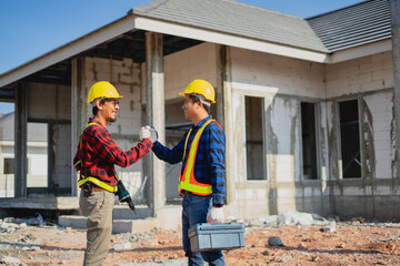 Male construction workers joining hands to build a house in the construction site.