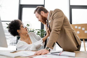 shocked african american woman pushing away businessman in office.