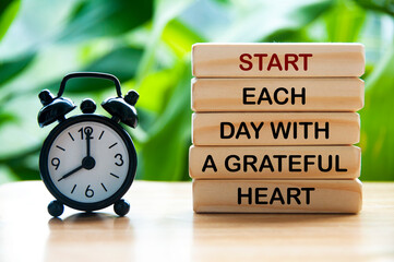 Start each day with a grateful heart text on wooden blocks with alarm clock and nature background....