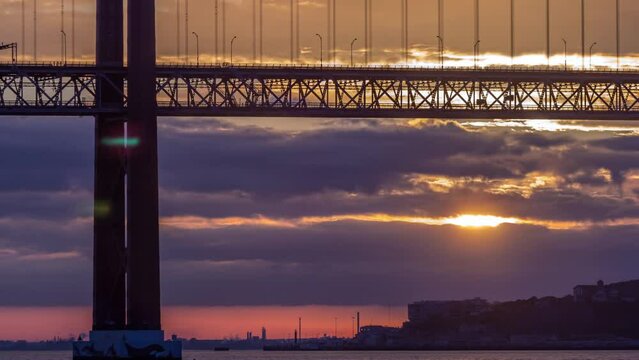 Lisbon city sunrise with April 25 bridge timelapse close up view, River and waterfront early morning. Purple clouds