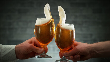 Two glasses of beer in cheers gesture, splashing.