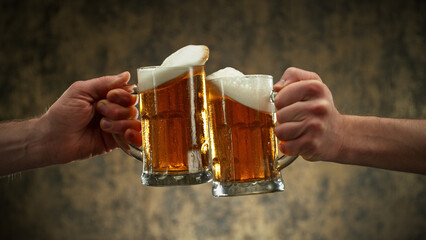 Two glasses of beer in cheers gesture, splashing.