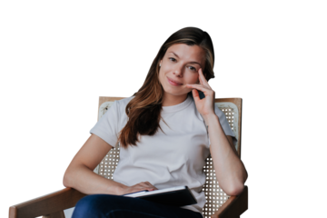 Confident brunette woman in white t-shirt and blue jeans sits on chair with laptop leaning on hand looks at camera against transparent background. Satisfied Spanish woman with loose hair relaxing home